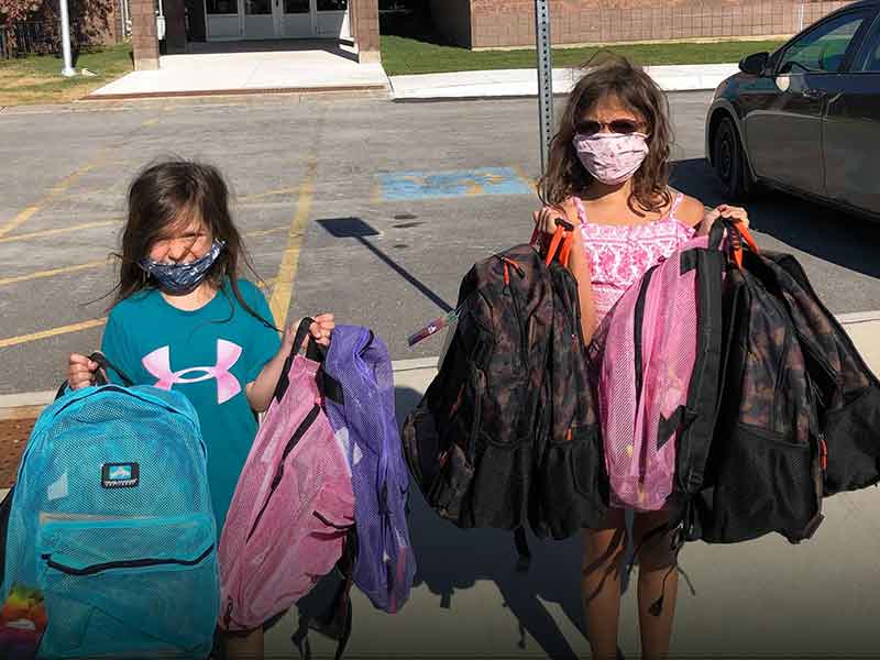 Two girls holding backpacks