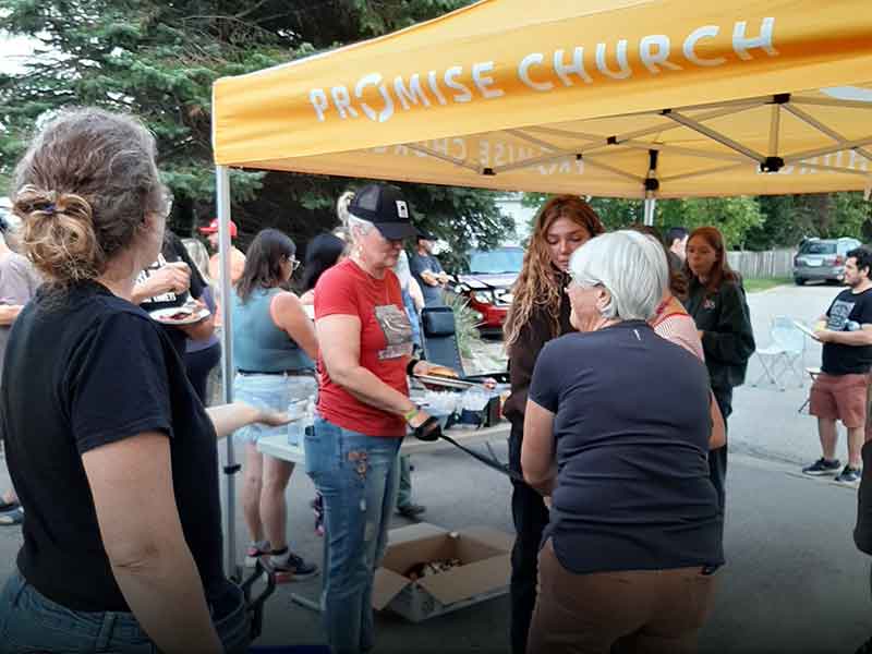 A group of people gathered under a yellow tent for a barbecue