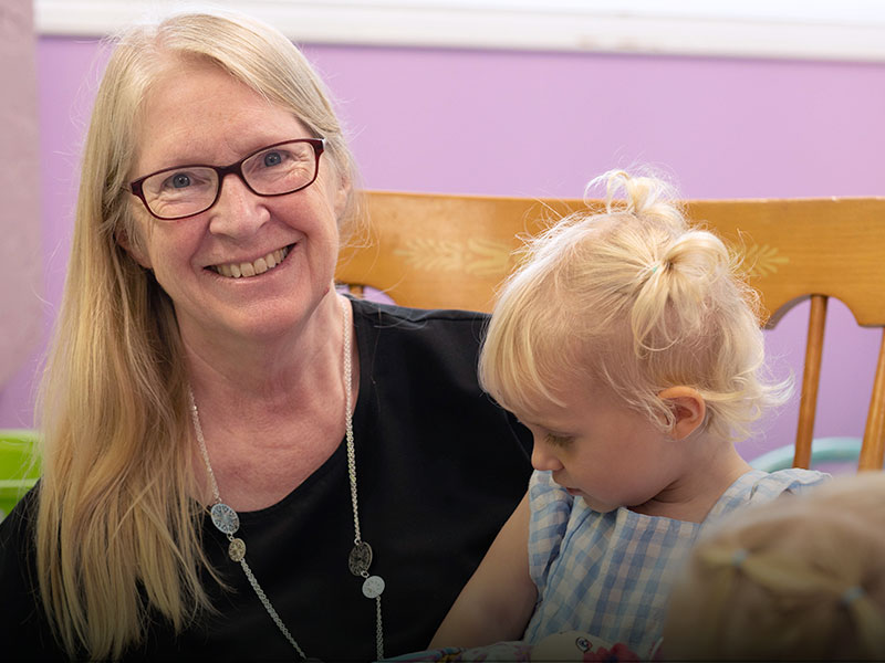 A nursery worker smiling with a child